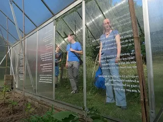 Bianca Boer in een kas achter een glazen wand met een handgeschreven gedicht